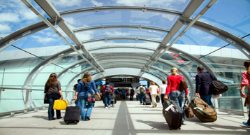 passengers with luggage walking through glass tunnel passengers with luggage walking through glass tunnel